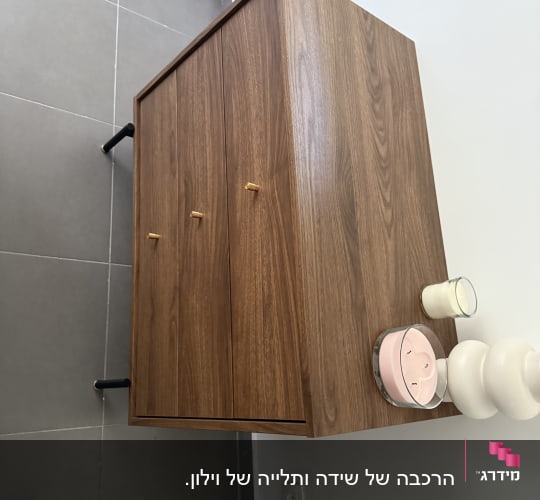 ארון עץ עם נר ומנורה על רצפה אפורה